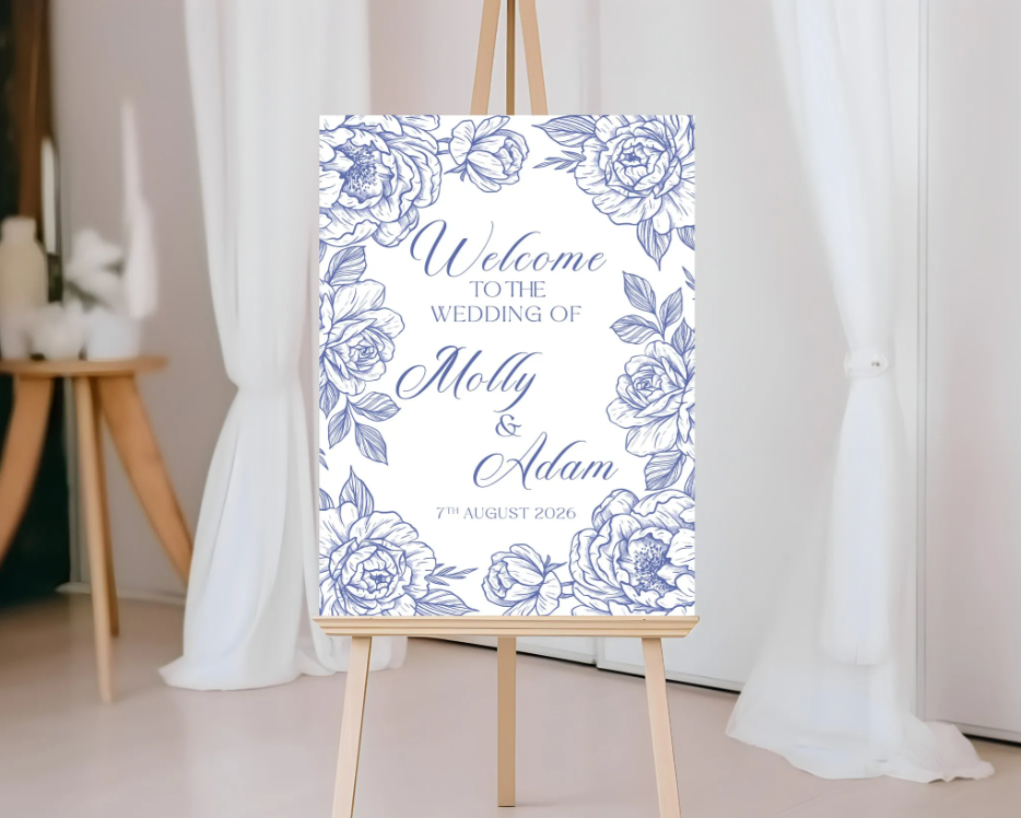 Wedding welcome sign with floral design on an easel against a white curtain background