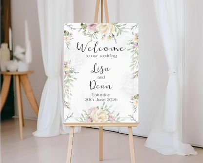 Wedding welcome sign with floral design on an easel against a white curtain background