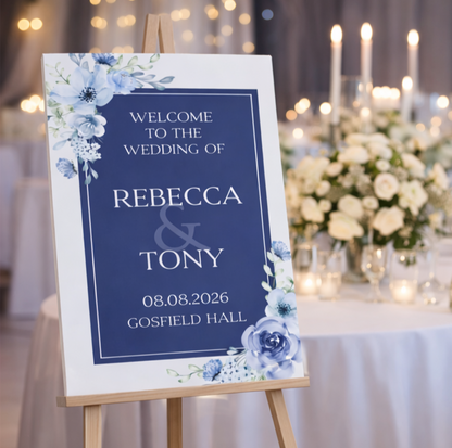 Wedding welcome sign with floral design on an easel in a decorated room.